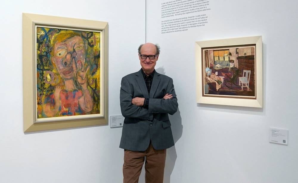 James Warhola, US artist and illustrator, stands next to his uncle Andy Warhol’s ‘Nosepicker 1: Why Pick on Me’ and ‘Living Room’ on display November 10, 2022 at Phillips Auction House in New York. — AFP pic