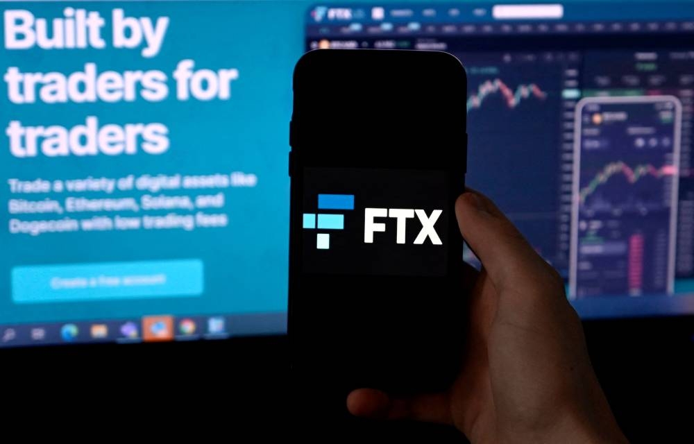 In this file photo illustration taken on February 9, 2022, a smart phone screen is seen displaying the logo of FTX, the crypto exchange platform, with a screen showing the FTX website in Arlington, Virginia. — AFP pic