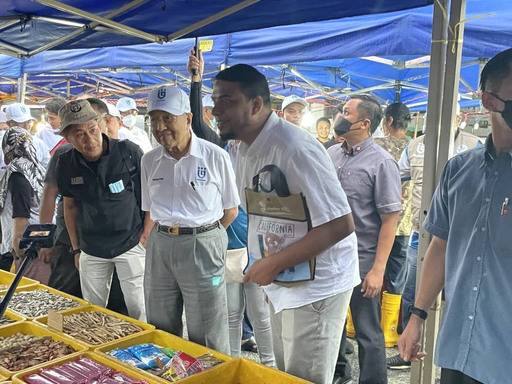 Tun Dr Mahathir Mohamad (centre) visiting night market vendors alongside Pejuang’s Shah Alam candidate Muhammad Rafique Abd Rashid, November 9, 2022. — Picture by Radzi Razak