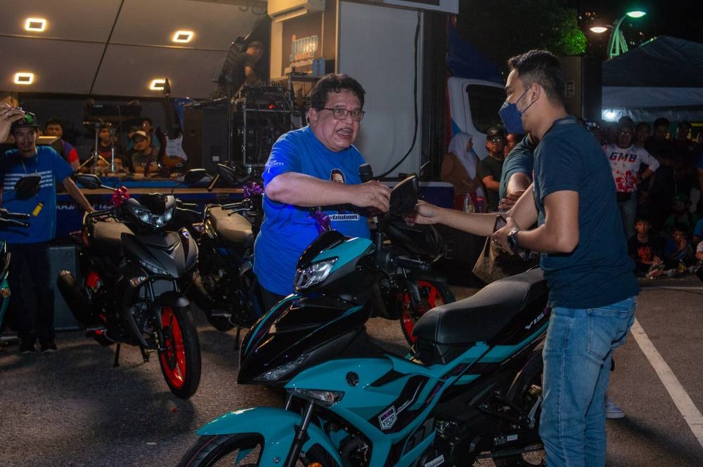 Barisan Nasional’s Datuk Seri Tengku Adnan Tengku Mansor hands over the key of a moped to the winner of a lucky draw during his youth-oriented event in Precinct 18, Putrajaya, October 29, 2022. — Picture by Shafwan Zaidon