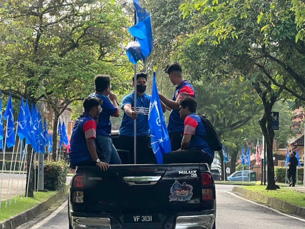 Barisan Nasional volunteers go round Putrajaya to stick the coalition’s flags at the roadside for the 15th general election campaigning. — Picture courtesy of Facebook/BN Comms
