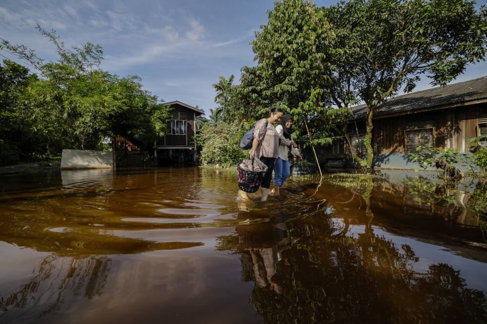 Two women wade through floodwater in Kampung Johan Setia in Klang, November 17, 2022. — Bernama pic 