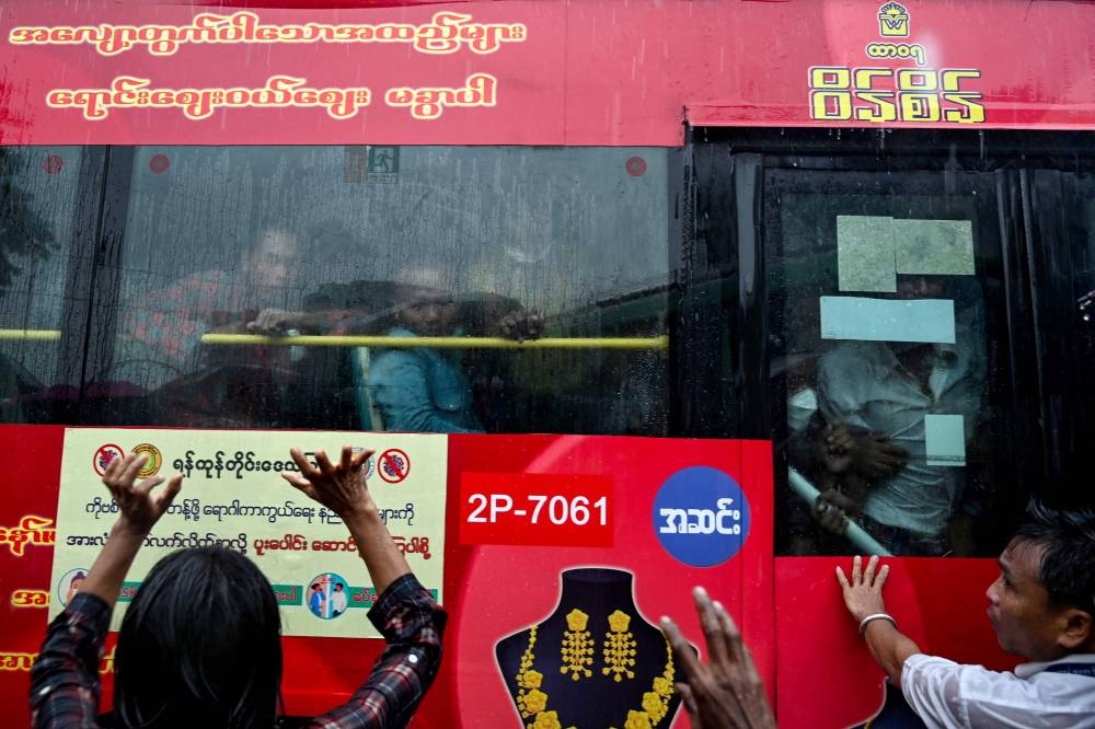 Relatives gather around a bus carrying prisoners being released outside the Insein prison in Yangon on November 17, 2022. — AFP pic