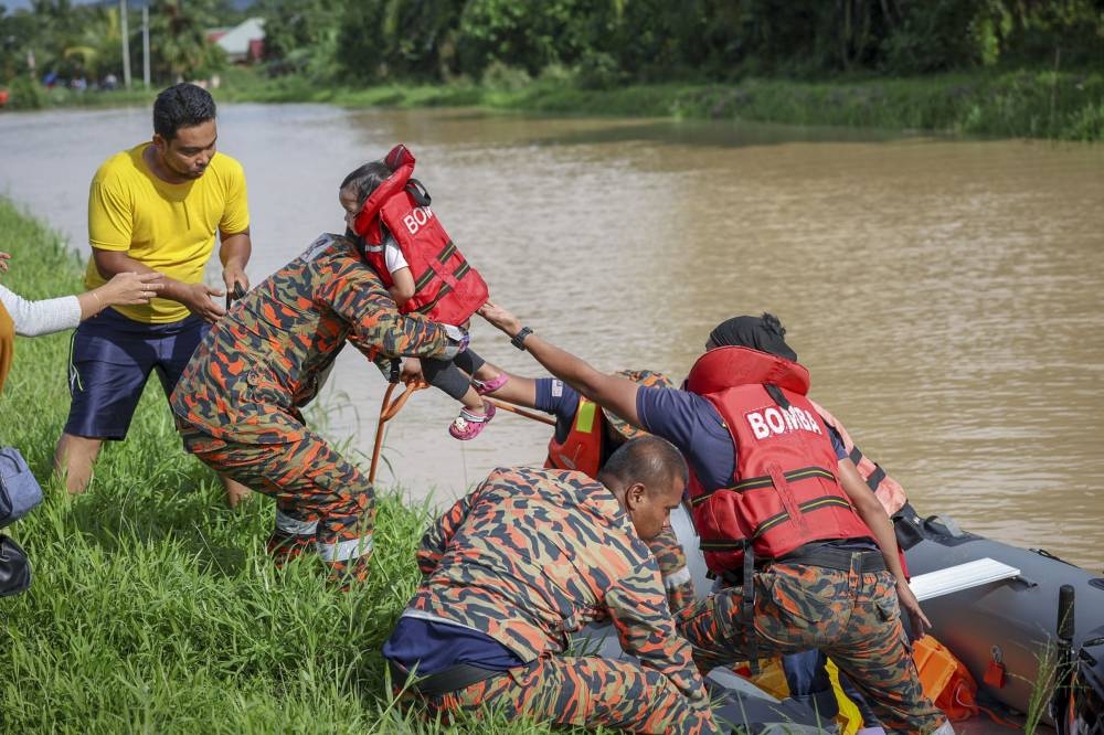 Dengkil Fire and Rescue Dept personnel evacuate a family caught in the flood in Kampung Sri Tanjung, Dengkil, November 17, 2022. — Bernama pic 