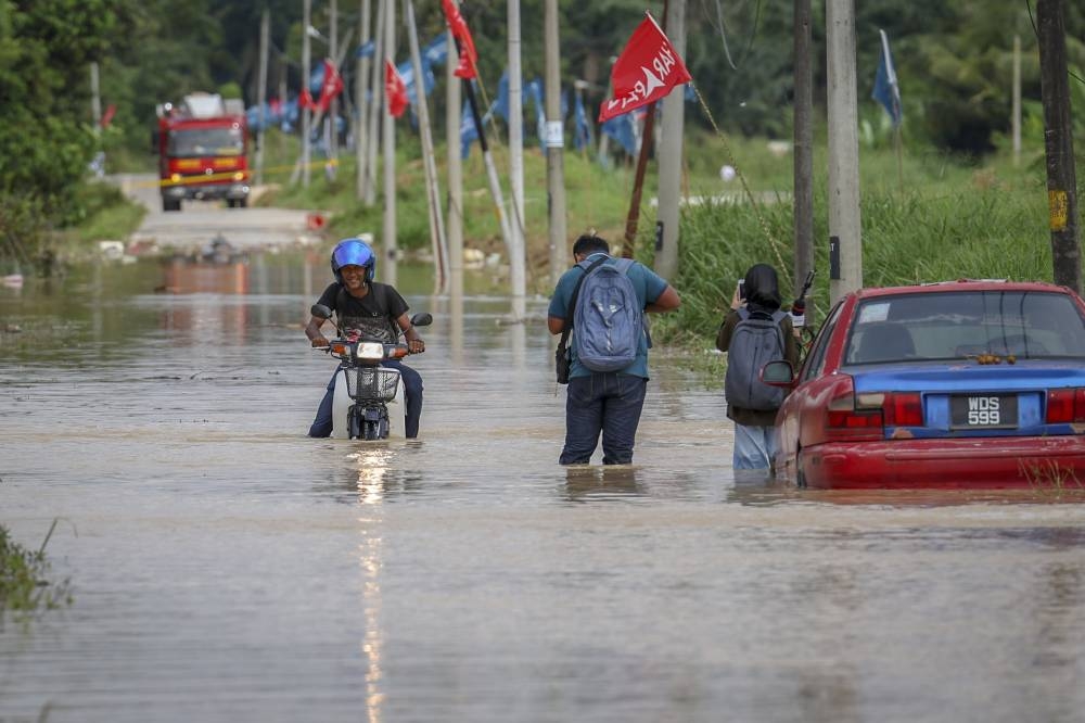 A motorcyclist attempts to traverse a flooded road resulting from the overflow at Sungai Langat in Kampung Sri Tanjung, November 17, 2022. — Bernama pic 