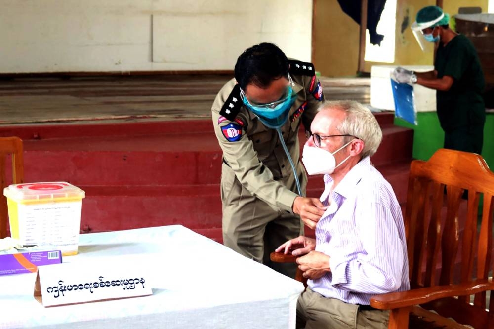 In this file handout photo from the state-run Myanmar News Agency (MNA) taken on July 28, 2021 and received on July 29, Sean Turnell, a detained Australian adviser to Myanmar's deposed leader Aung San Suu Kyi, gets vaccinated against the Covid-19 coronavirus in Insein prison in Yangon. ― AFP pic