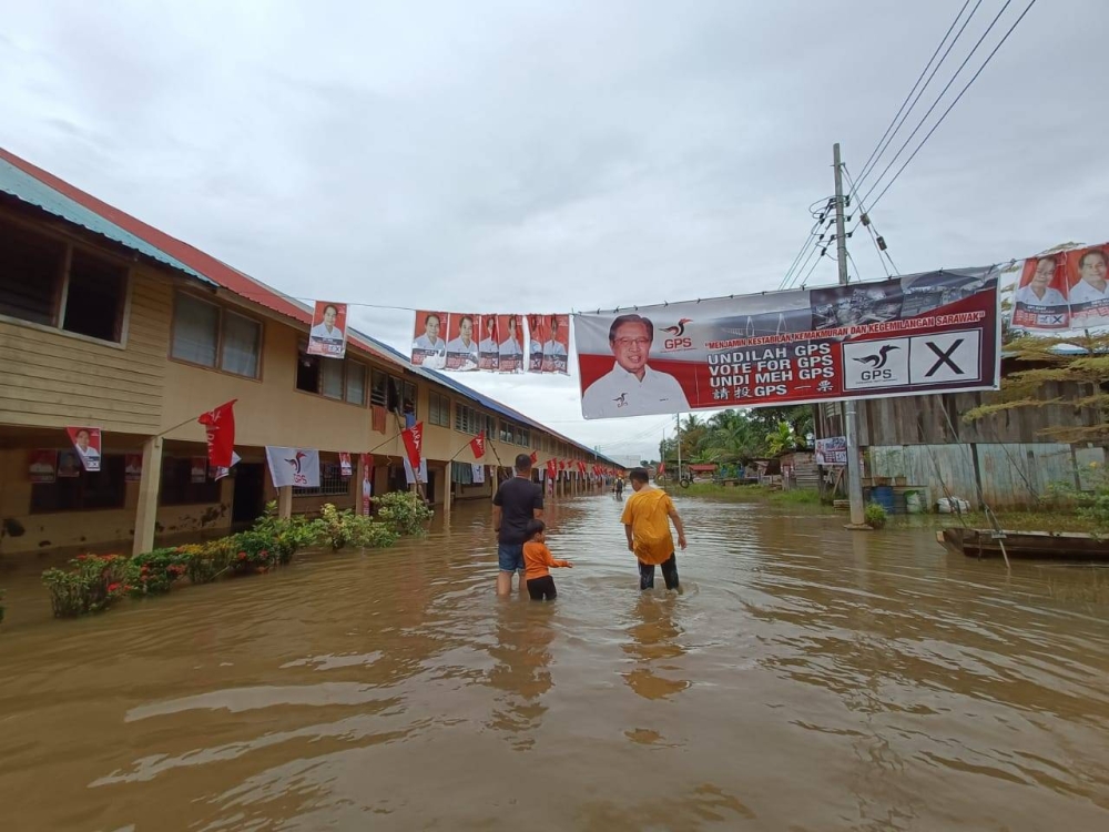 Some Long Bemang residents walk through floodwaters to go to the polling centre at SK Long Bemang. ― Borneo Post pic