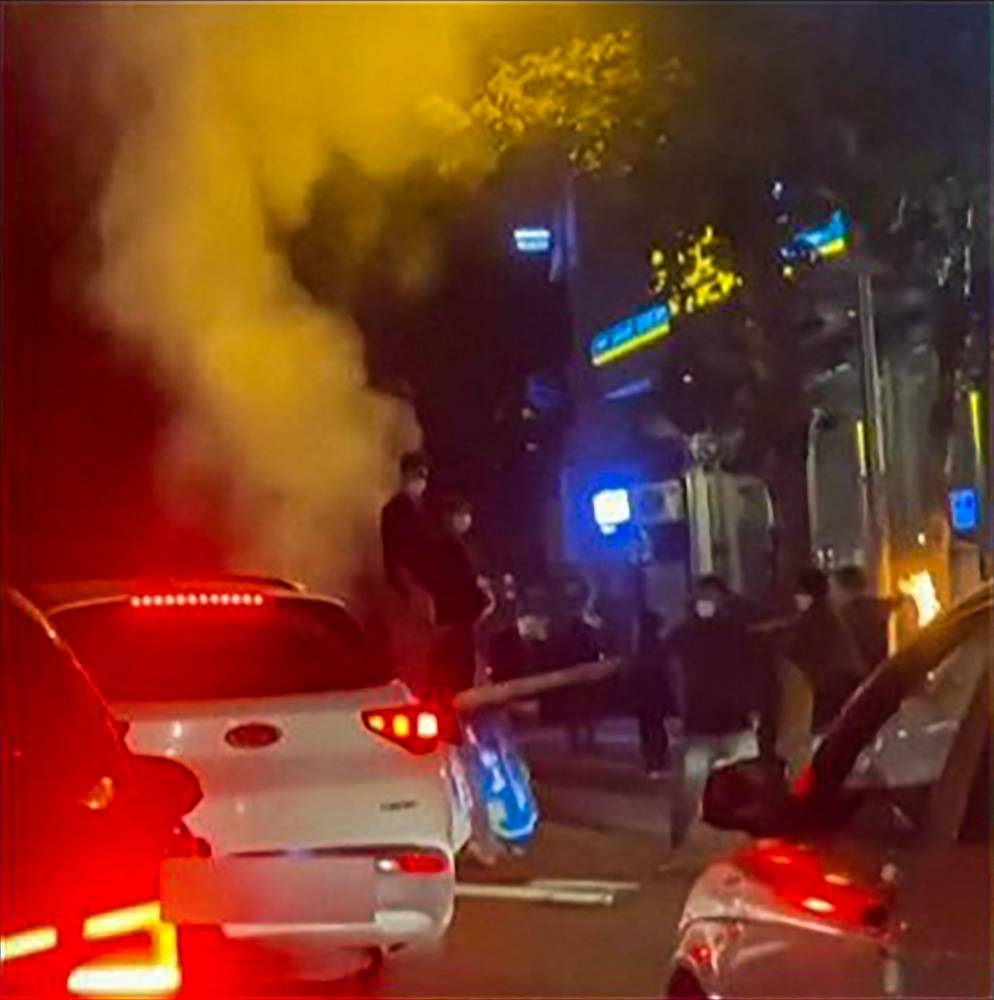 This grab taken from a UGC video made available on the ESN platform on November 15, 2022, shows Iranian protesters blocking traffic in the northern city of Rasht as they chant ‘freedom’ while removing a street sign. — AFP pic