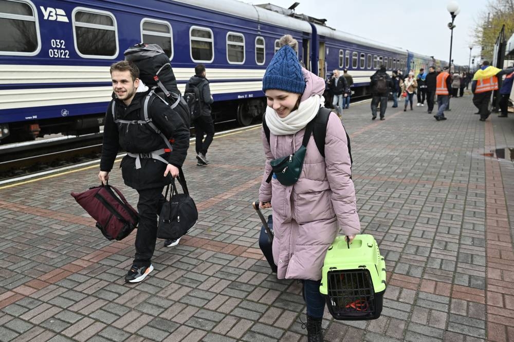Passengers walk with luggage along the first train from Kyiv to Kherson since the Russian invasion of Ukraine, which arrived at the Kherson train station on November 19, 2022.— AFP pic
