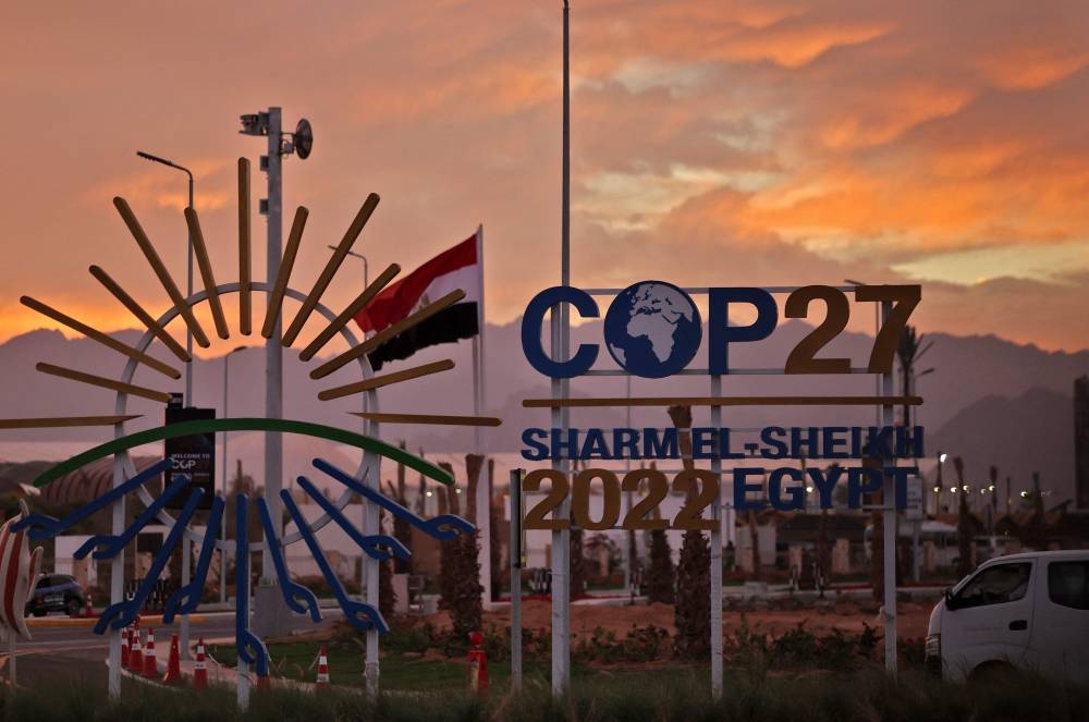 The sun sets behind the sign showing the logo of the COP27 climate conference at the Sharm el-Sheikh International Convention Centre, in Egypt's Red Sea resort city of the same name, on Novmeber 14, 2022. — AFP pic