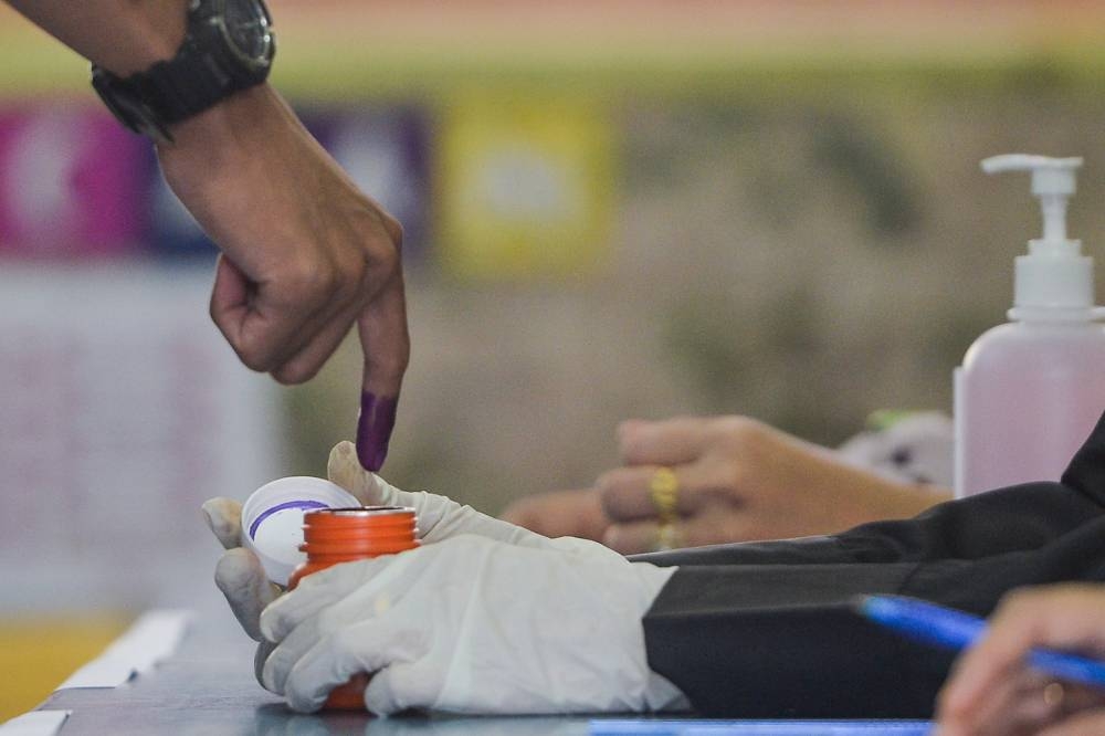 An Election Commission officer dips a voter finger in indelible ink during the 15th general election at Sekolah Kebangsaan Puncak Alam 2 November 19, 2022. — Picture by Miera Zulyana