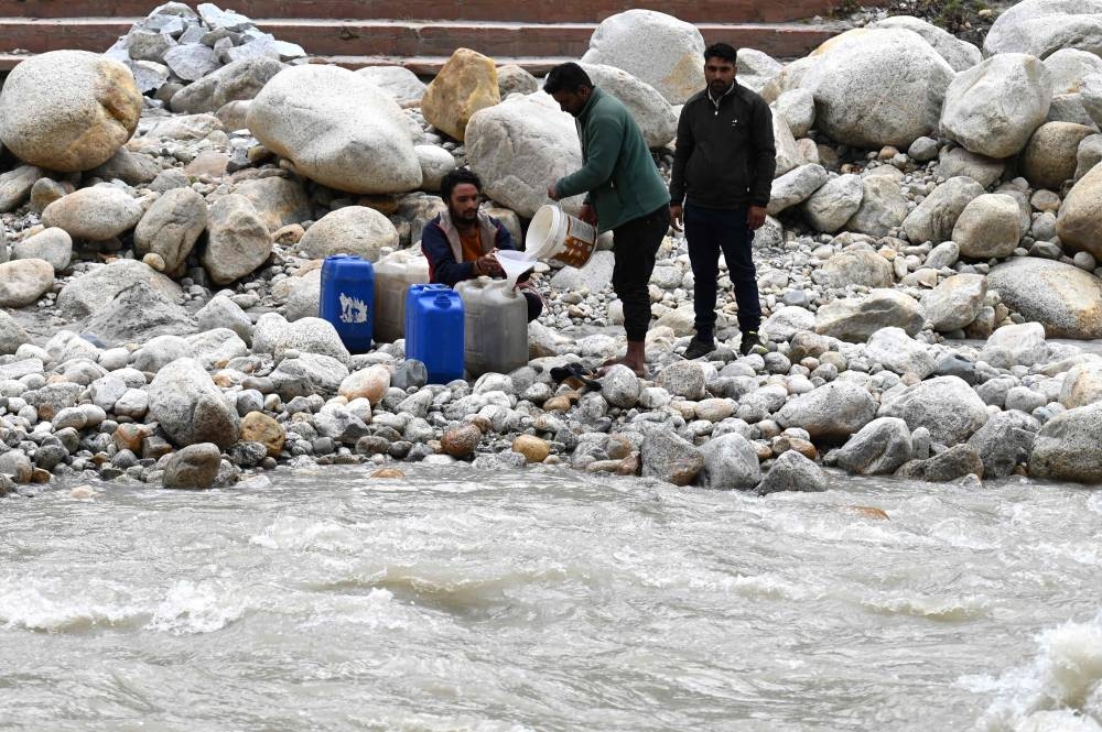 Daily wage workers fill cans with the meltwater of Gangotri glacier which is the primary source of the pious river Ganges, in Uttarakhand September 15, 2022. — AFP pic