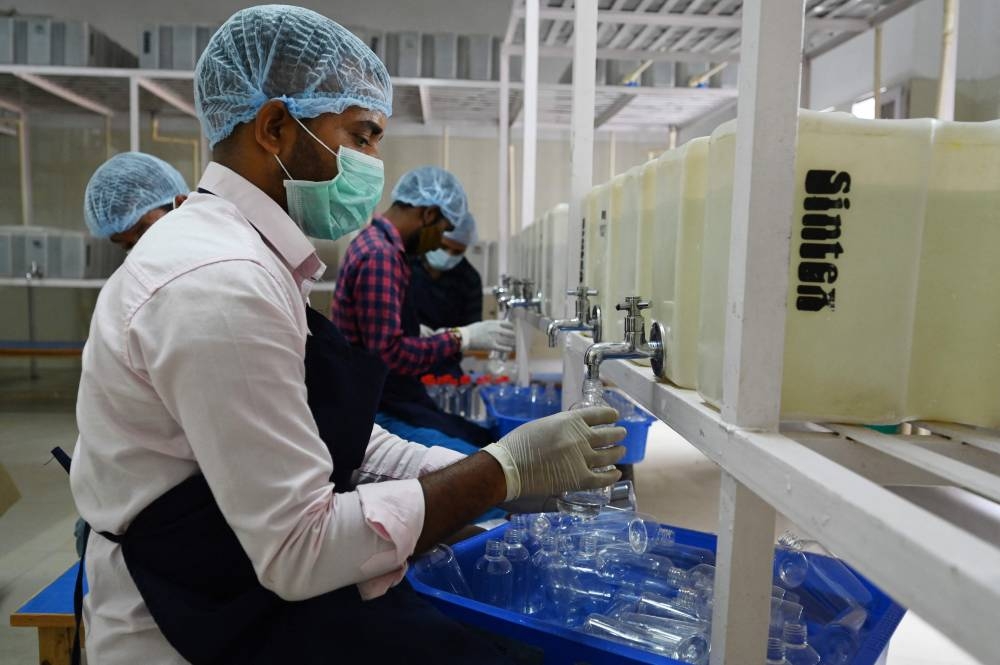 Daily wage workers fill bottles with meltwater of Gangotri glacier which is the primary source of the pious river Ganges, at the Indian Post office in Uttarkashi September 14, 2022. — AFP pic