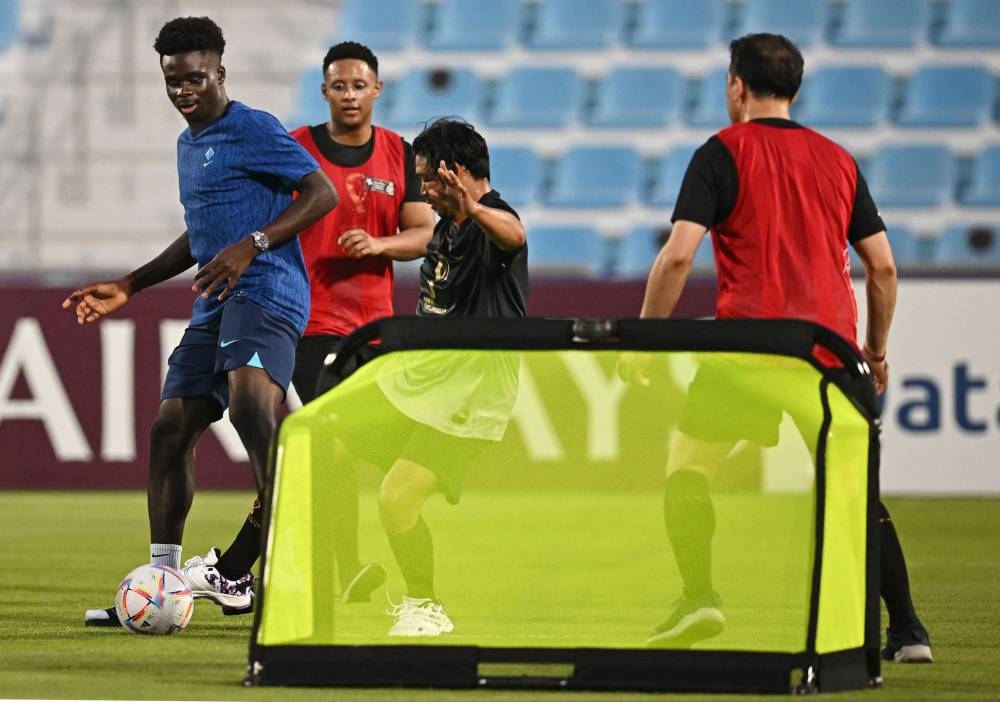 England’s forward Bukayo Saka plays football with migrant workers during a meeting at the Al Wakrah Stadium in Doha, November 17, 2022, ahead of the Qatar 2022 World Cup football tournament. — AFP pic 