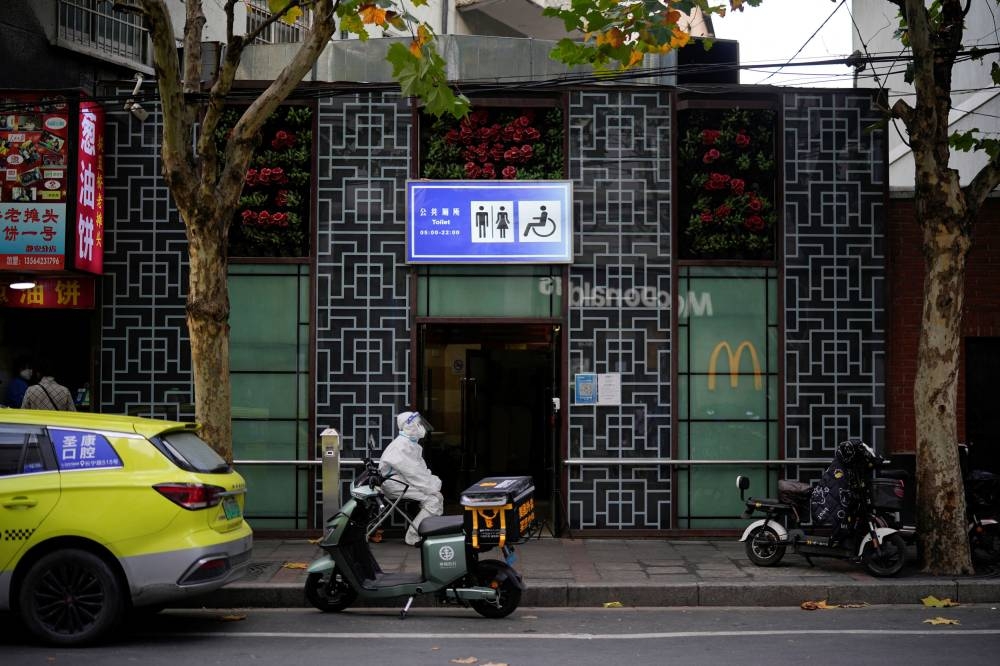 A worker in protective suit keeps a watch outside a public toilet to inspect the health code of visitors, amid the coronavirus disease outbreak in Shanghai November 21, 2022. — Reuters pic