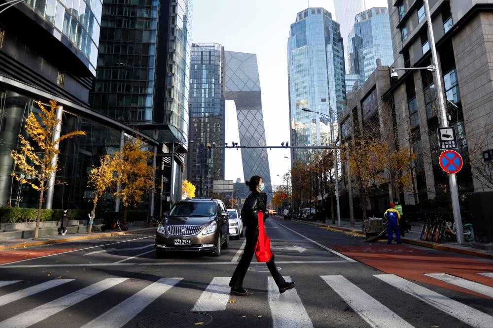 A woman walks across the street during morning rush hour, following the outbreak of the coronavirus disease, in the Central Business District in Chaoyang District, Beijing November 21, 2022. — Reuters pic