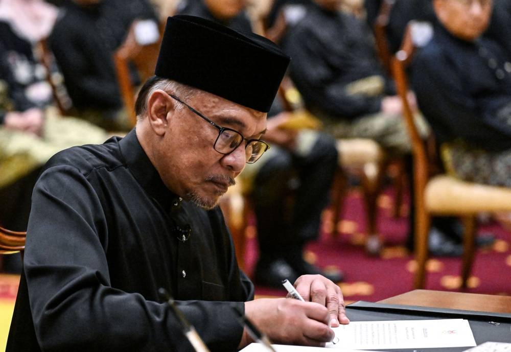 Malaysia’s newly appointed Prime Minister Datuk Seri Anwar Ibrahim signs documents after taking the oath during the swearing-in ceremony at the National Palace in Kuala Lumpur, Malaysia, November 24, 2022. — Reuters pic 