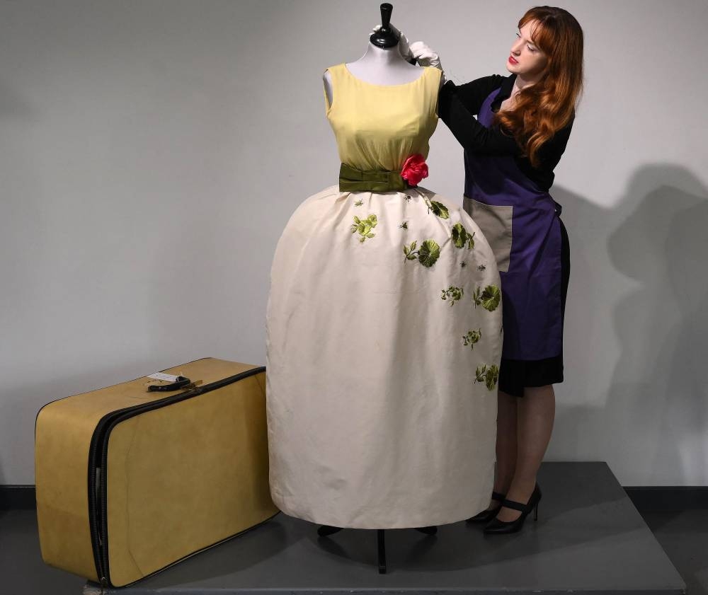 An employee poses with a Christian Dior dress worn by actress Elizabeth Taylor, and recently discovered with other dresses in a suitcase, ahead of their sale at Kerry Taylor Auctions, in London on November 25, 2022. — AFP pic