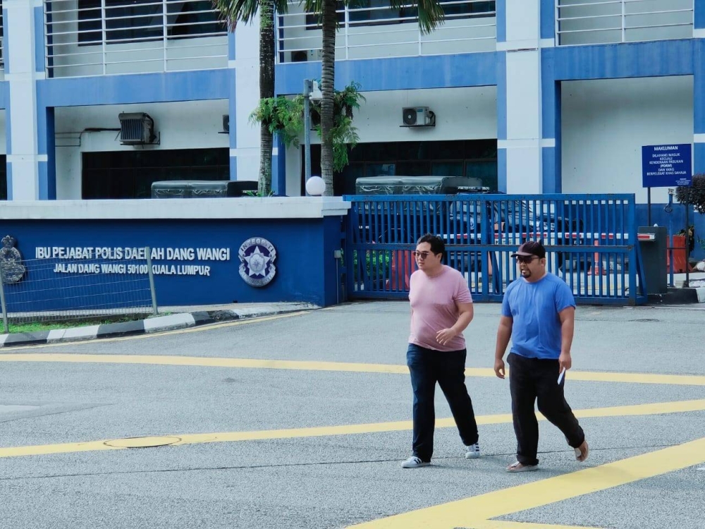 Zulfadzli Halim (right), who goes by the moniker Bumilangit on Twitter, leaving the Dang Wangi district police headquarters in KL with a friend after being released from remand November 26, 2022. — Picture By Radzi Razak