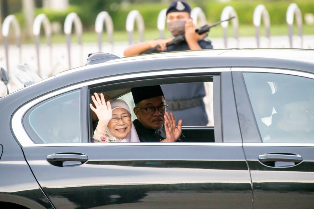 Prime Minister Datuk Seri Anwar Ibrahim and his wife Datin Seri Dr Wan Azizah Wan Ismail wave from their car after the swearing-in ceremony at Istana Negara, November 24, 2022. — Picture by Firdaus Latif