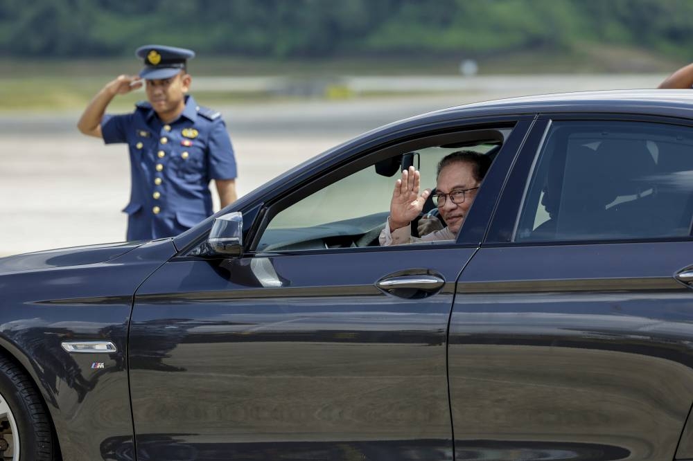Prime Minister Datuk Seri Anwar Ibrahim waves to media practitioners in the official car driven by the Sultan of Brunei Sultan Hassanal Bolkiah. — Bernama pic