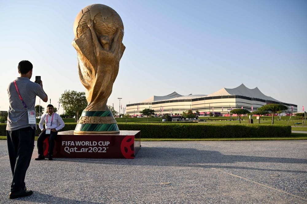 A man takes a picture of a Fifa World Cup trophy replica in front of the Al-Bayt Stadium in al-Khor on November 10, 2022, ahead of the Qatar 2022 Fifa World Cup football tournament. The police detained 152 individuals for their alleged involvement in online gambling activities involving the Qatar World Cup football matches. — AFP pic