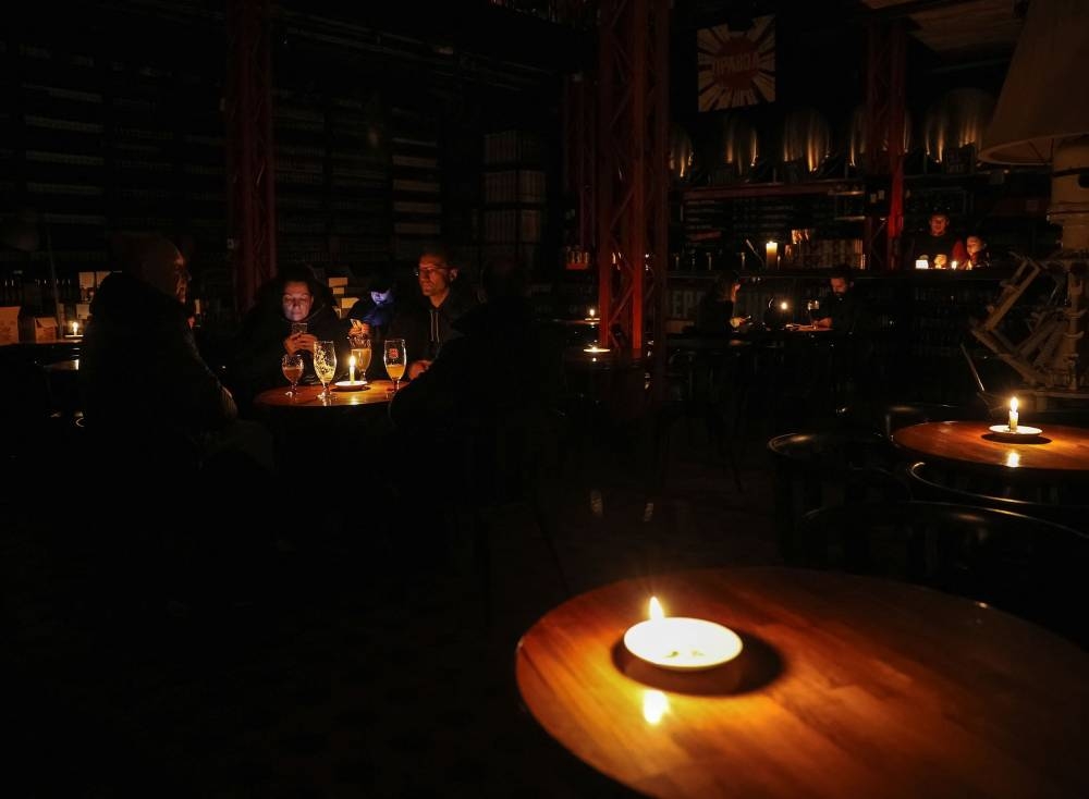 People sit in a pub lit with candles during a power outage after critical civil infrastructure was hit by Russian missile attacks, as Russia's invasion of Ukraine continues, in Lviv, Ukraine November 24, 2022. — Reuters pic