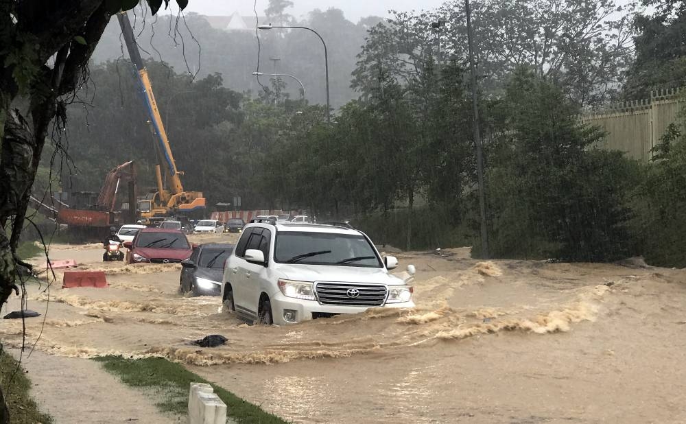 Cars traverse Lebuhraya Sultan Iskandar heading to Jalan Tun Razak from Jalan Tuanku Abdul Halim near the Parliament building, during a flash flood after a downpour around 3pm today, November 30, 2022. — Bernama pic 