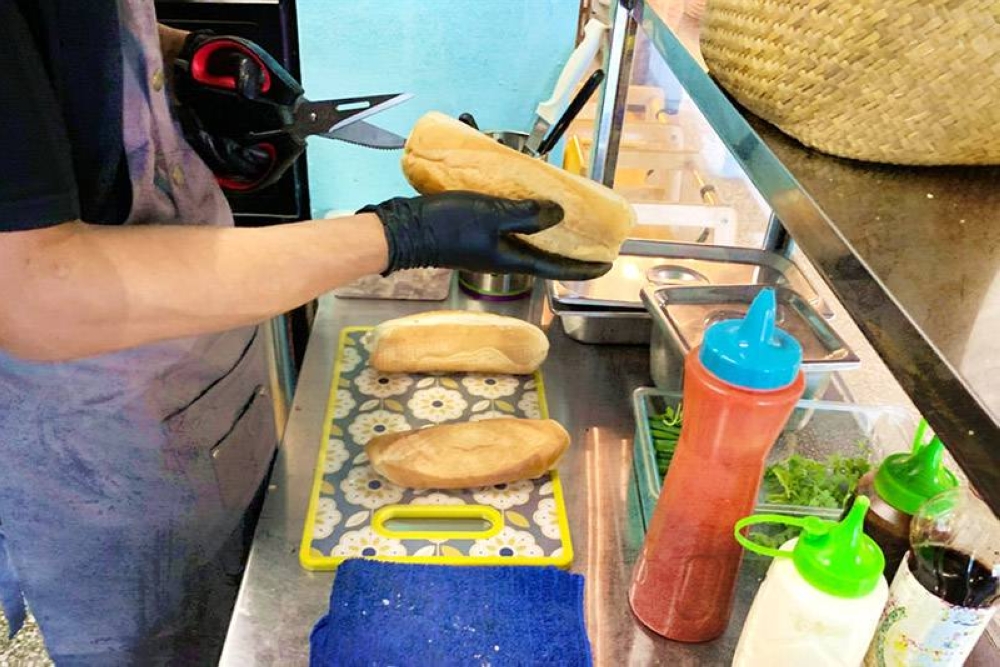 Slicing a crusty baguette — freshly baked daily — to make the 'banh mi.'