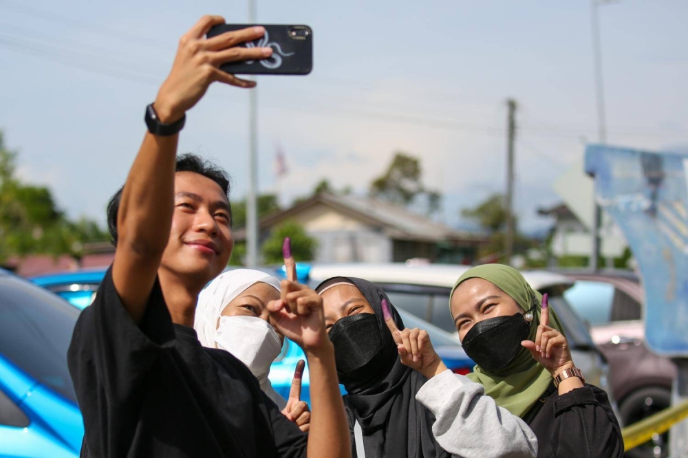 Young voters taking a wefie with their ink-stained index fingers after voting at a polling centre in Satok, Kuching on Nov 19, 2022. — TODAY pic