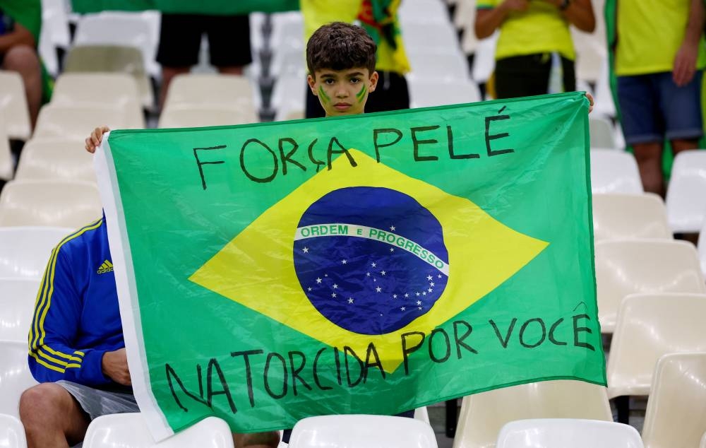 A fan poses with a flag of Brazil bearing a message for Pele before the match between Cameroon and Brazil at the Lusail Stadium, Lusail December 2, 2022. — Reuters pic 