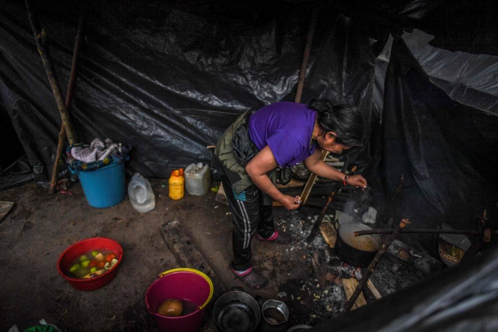 In this file photo taken on February 07, 2022 an Embera indigenous woman cooks in a makeshift camp at a national park in Bogota. — AFP pic