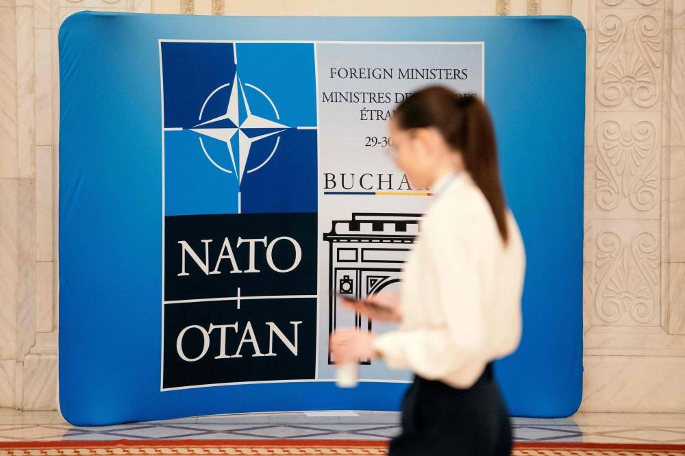 A woman walks past the NATO logo during the meeting of the NATO Ministers of Foreign Affairs in Bucharest, Romania, on November 30, 2022. — AFP pic