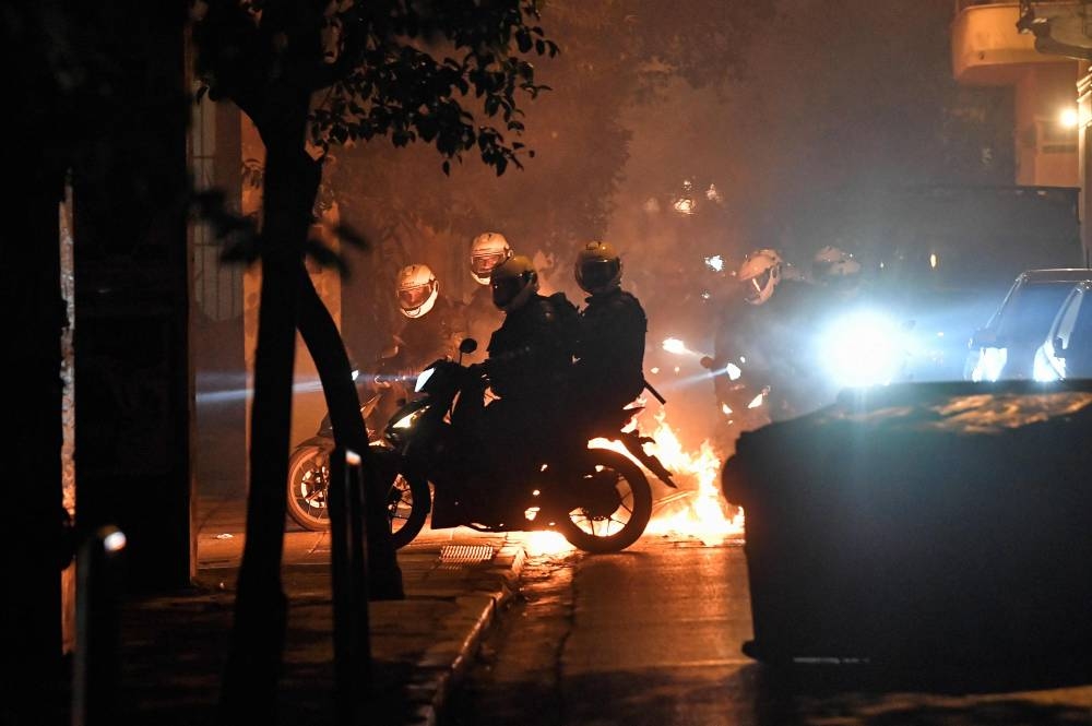 Motorised police chases protesters during clashes on the sidelines of a rally against police violence, marking the 14th anniversary of the 2008 fatal police shooting of a teenager in central Athens' Exarchia neighbourhood on December 6, 2022. — AFP pic