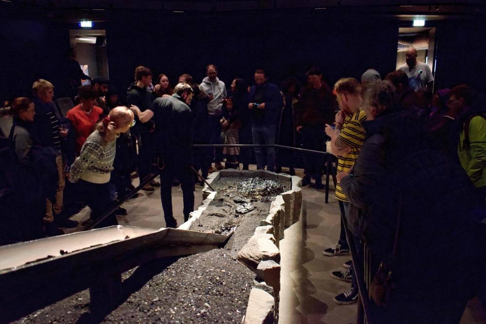 Scottish Lava Show host Iain MacKinnon (centre left) manipulates cooled lava as the spectators get closer to it at the showroom of the Lava Show in Reykjavik city center, Iceland, on December 1, 2022. — AFP pic