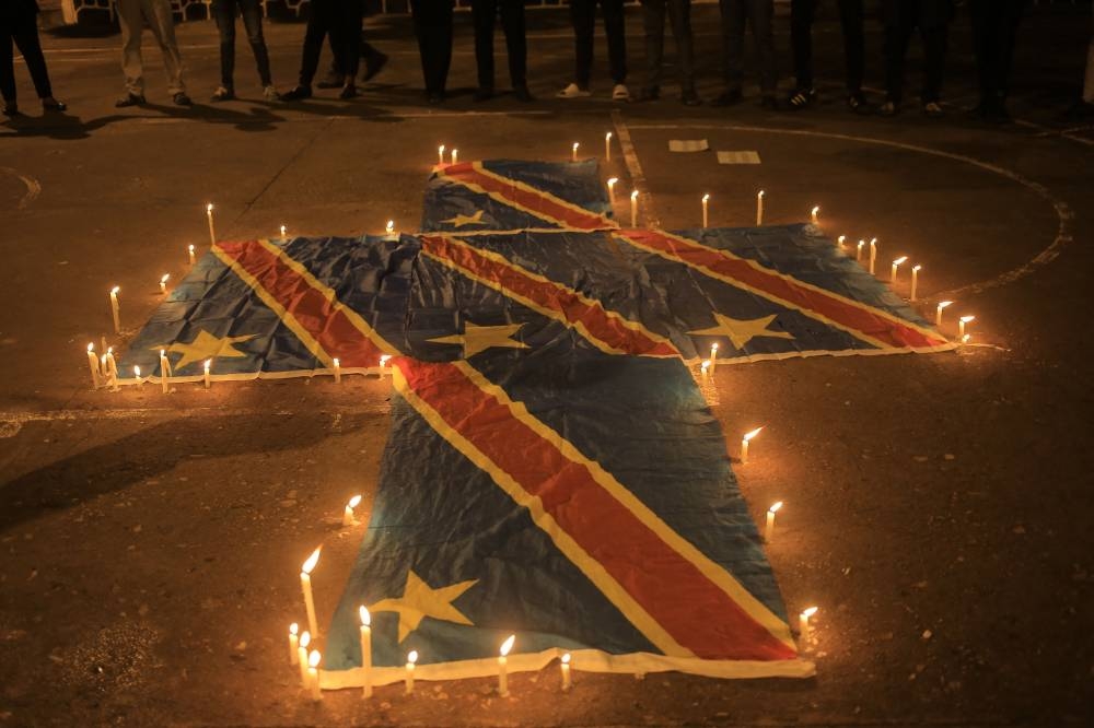 Flags of the Democratic Republic of Congo are surrounded by candles in beni on December 7, 2022 during a prayer vigil in remembrance of the victims of the ungoing unrest in the East of the country. — AFP pic