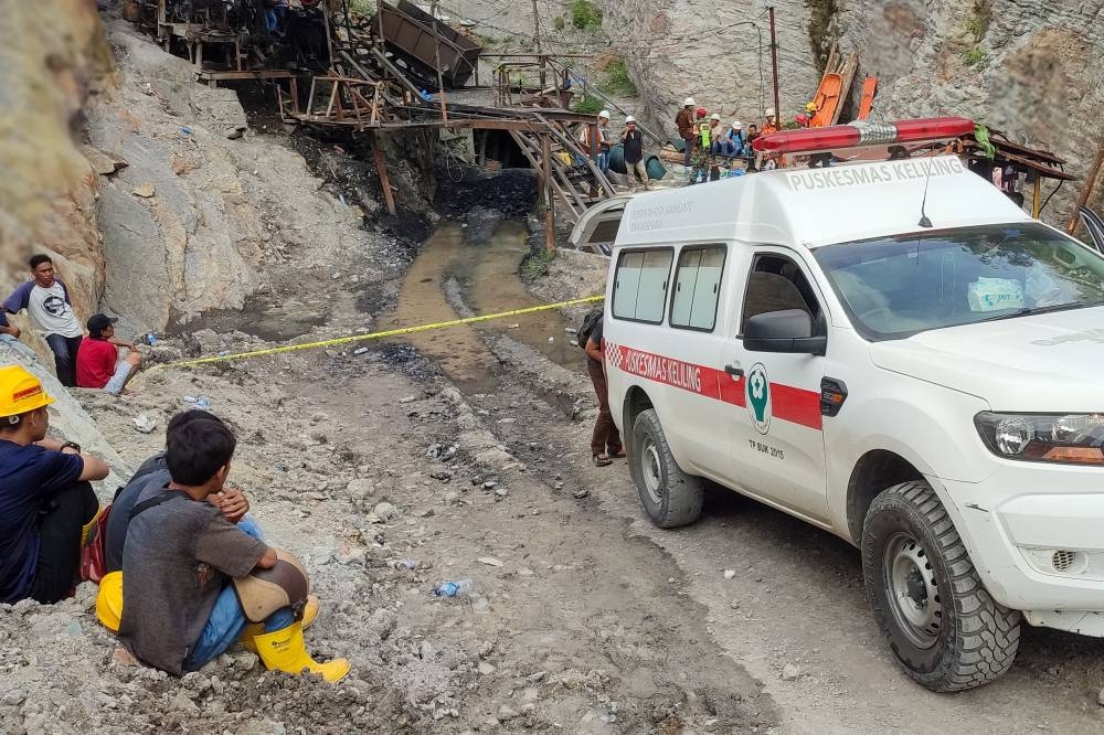 Surviving miners look on as rescue teams evacuate dead and injured victims of a coal mine explosion in Sawahlunto on December 9, 2022. — AFP pic