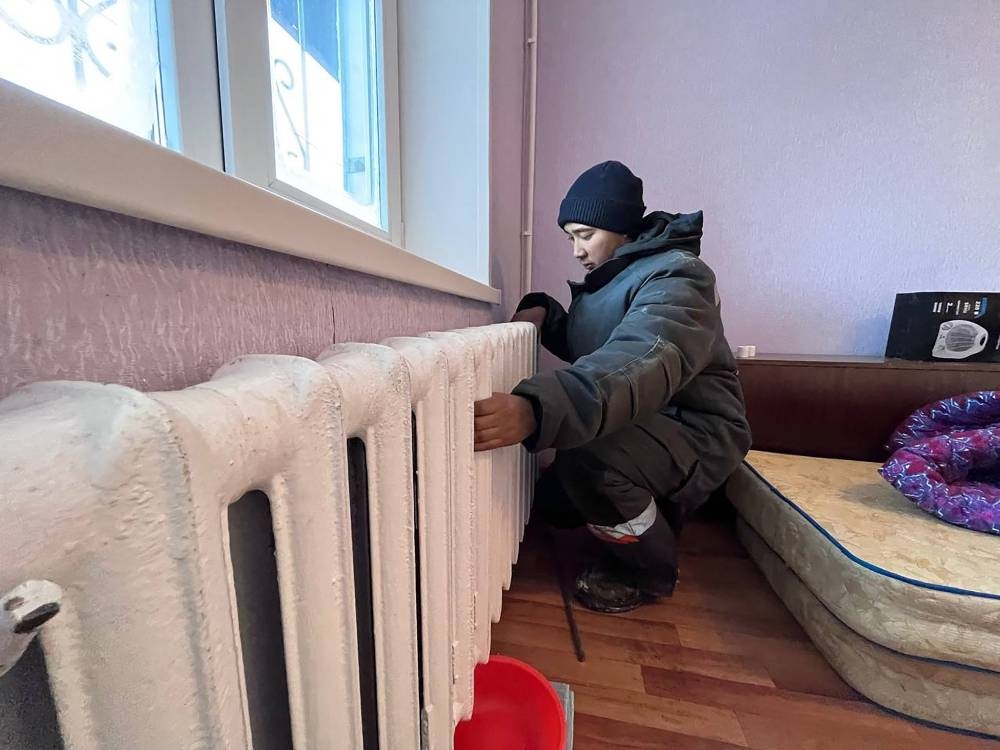 This undated handout photograph released on December 9, 2022 by the Kazakhstan’s Government press service shows a worker repairing radiators of the heating system in the apartment in Ekibastuz. — AFP pic