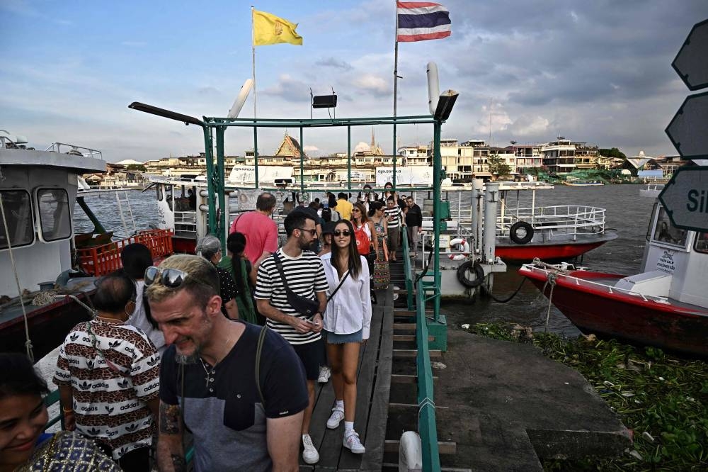 Tourists disembark from a commuter ferry on the Chao Praya River in Bangkok on December 9, 2022. — AFP pic