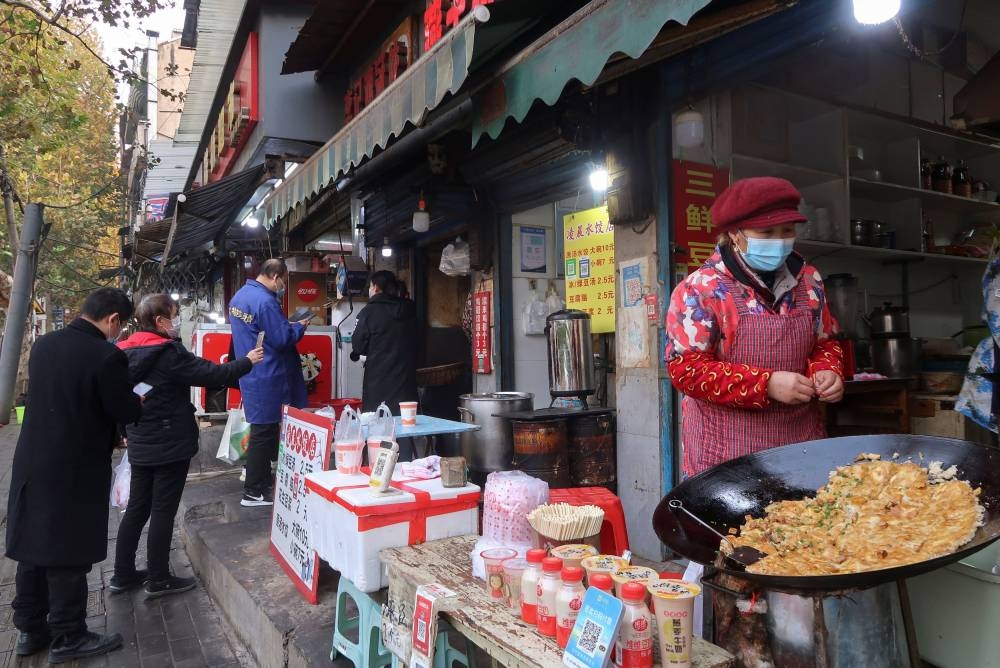 People line up at a food stall in the morning, after the government eased curbs on the coronavirus disease control, in Wuhan December 10, 2022. — Reuters pic