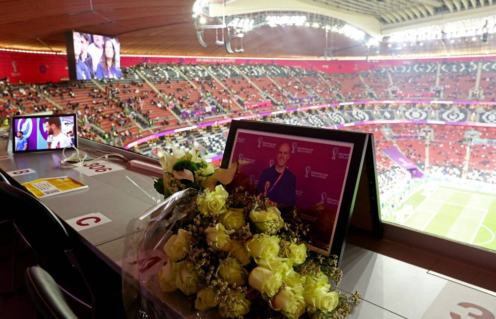 Flowers are laid at a media tribune desk in memory of the American journalist Grant Wahl, who passed away December 9 2022. — Reuters pic