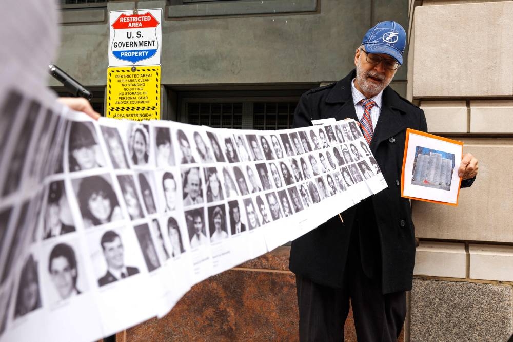 Paul Hudson, whose daughter Melina was one of the victims in the Pan Am Flight 103 Lockerbie bombing, holds up a banner of pictures of additional victims outside the federal court before the trial of a Libyan man accused of making the bomb that destroyed the plane, in Washington December 12, 2022. — Getty Images via AFP 