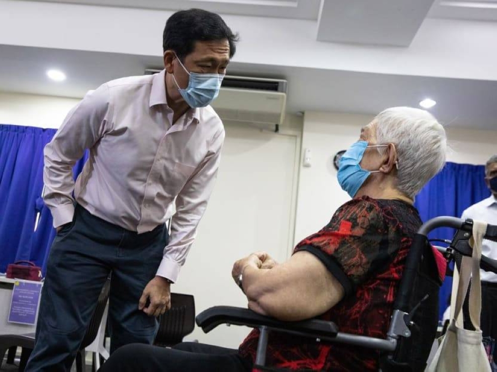 Singapore Health Minister Ong Ye Kung talking to woman who received the Covid-19 bivalent vaccine administered by the mobile vaccination team at Hong Kah Community Club on Dec 12, 2022. — TODAY pic