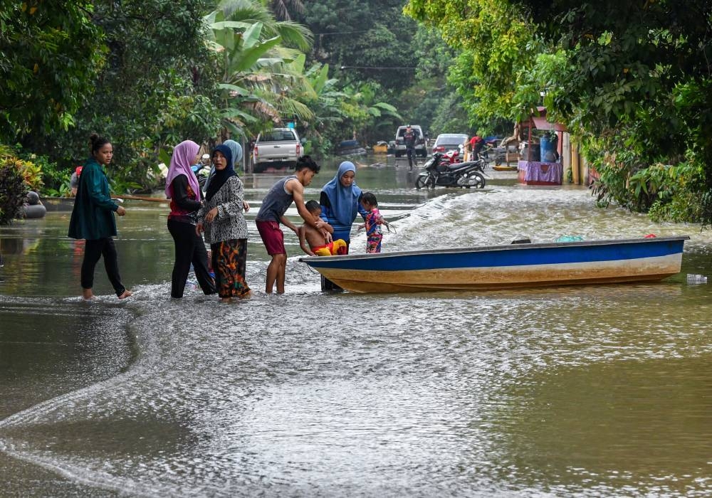 Flood victims put children on a boat during the floods at Kampung Tersang, Rantau Panjang in Pasir Mas December 13, 2022. — Bernama pic