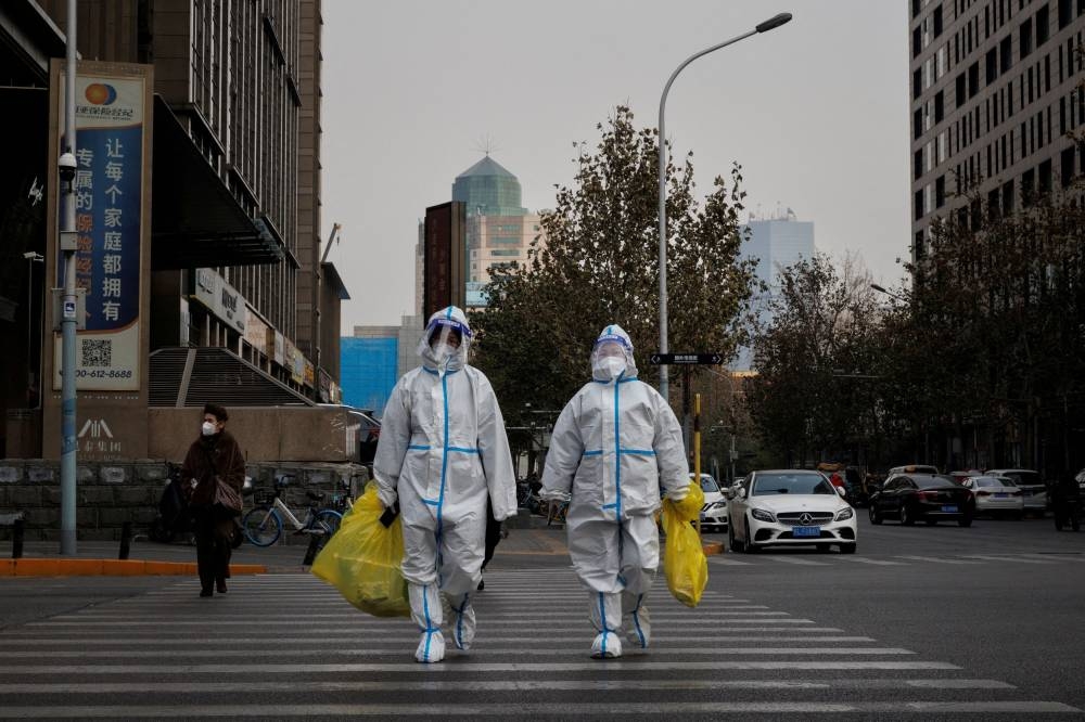Pandemic prevention workers in protective suits cross a street as coronavirus disease outbreaks continue in Beijing, December 9, 2022. — Reuters pic