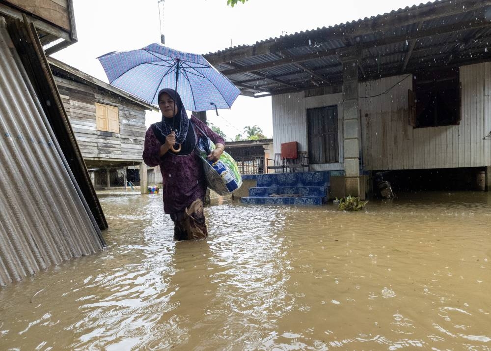 A woman wades through flood water to register for admission to a temporary evacuation centre at Sekolah Kebangsaan Kubang Kual following a three-day downpour in Pasir Mas, Kelantan, December 11, 2022. — Bernama pic 