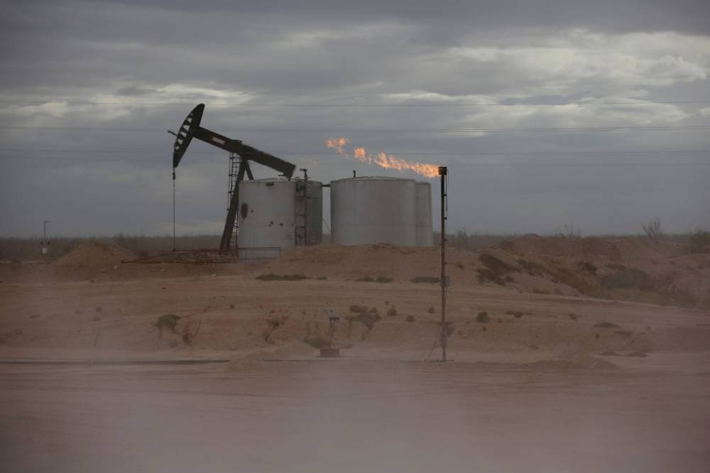 Dust blows around a crude oil pump jack and flare burning excess gas at a drill pad in the Permian Basin in Loving County, Texas November 25, 2019. — Reuters pic