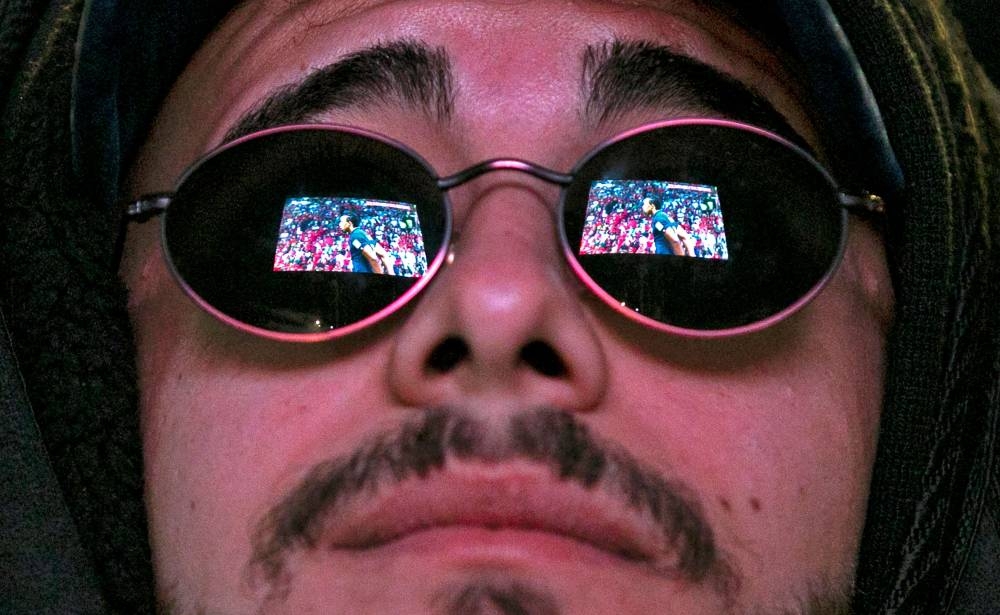 A screen is reflected against the sunglasses of an Iraqi football fan,  as he watches match between Morocco and France, in the southern Iraqi city of Nasiriyah December 14, 2022. — AFP pic