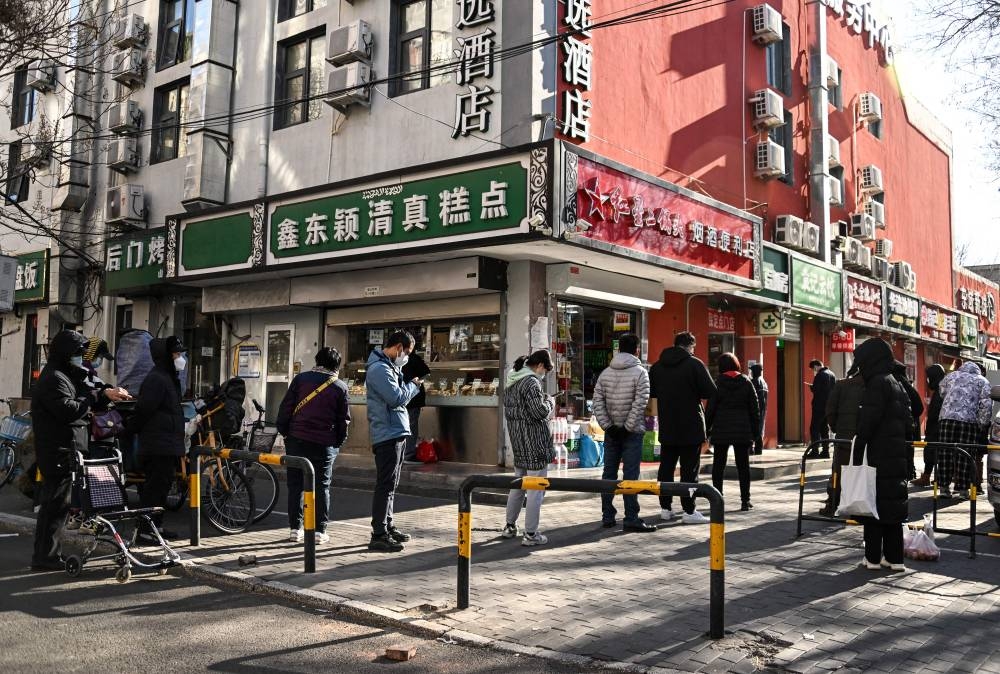 People wait in a queue to buy medicine from a pharmacy in Beijing on December 11, 2022. — AFP pic