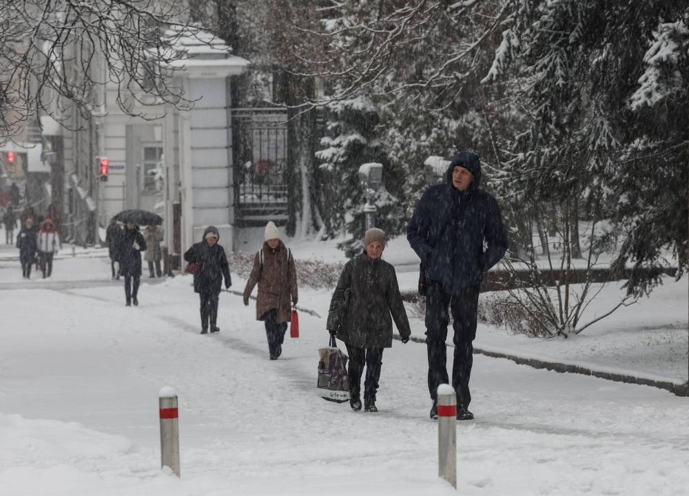 People walk down the street amid a snowfall as Russia's invasion of Ukraine continues, in central Kyiv, Ukraine December 12, 2022.  — Reuters pic